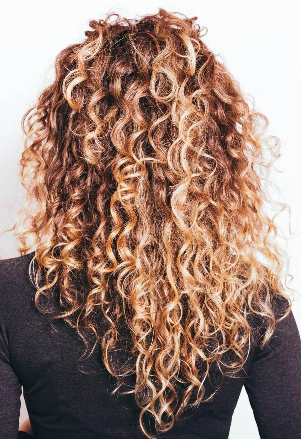 Lange, dunkelblonde, lockige Damenfrisur mit Dauerwelle für voluminöse Locken