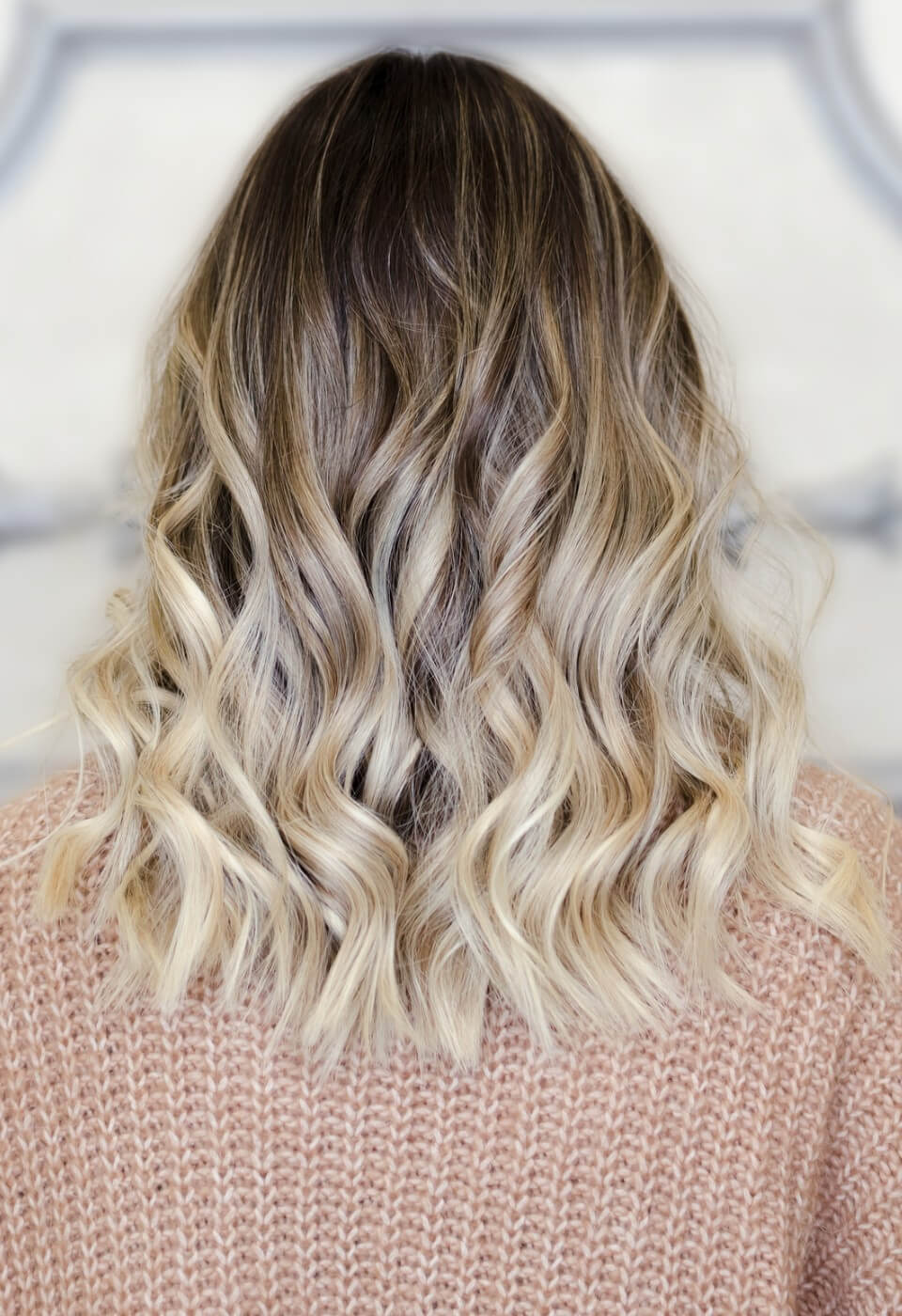 Mittellange, blonde, lockige Damenfrisur mit Volumenwelle für extra Fülle